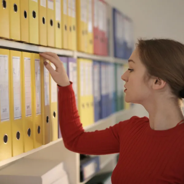Office worker pulling a binder from a shelf for setting up a small business chart of accounts